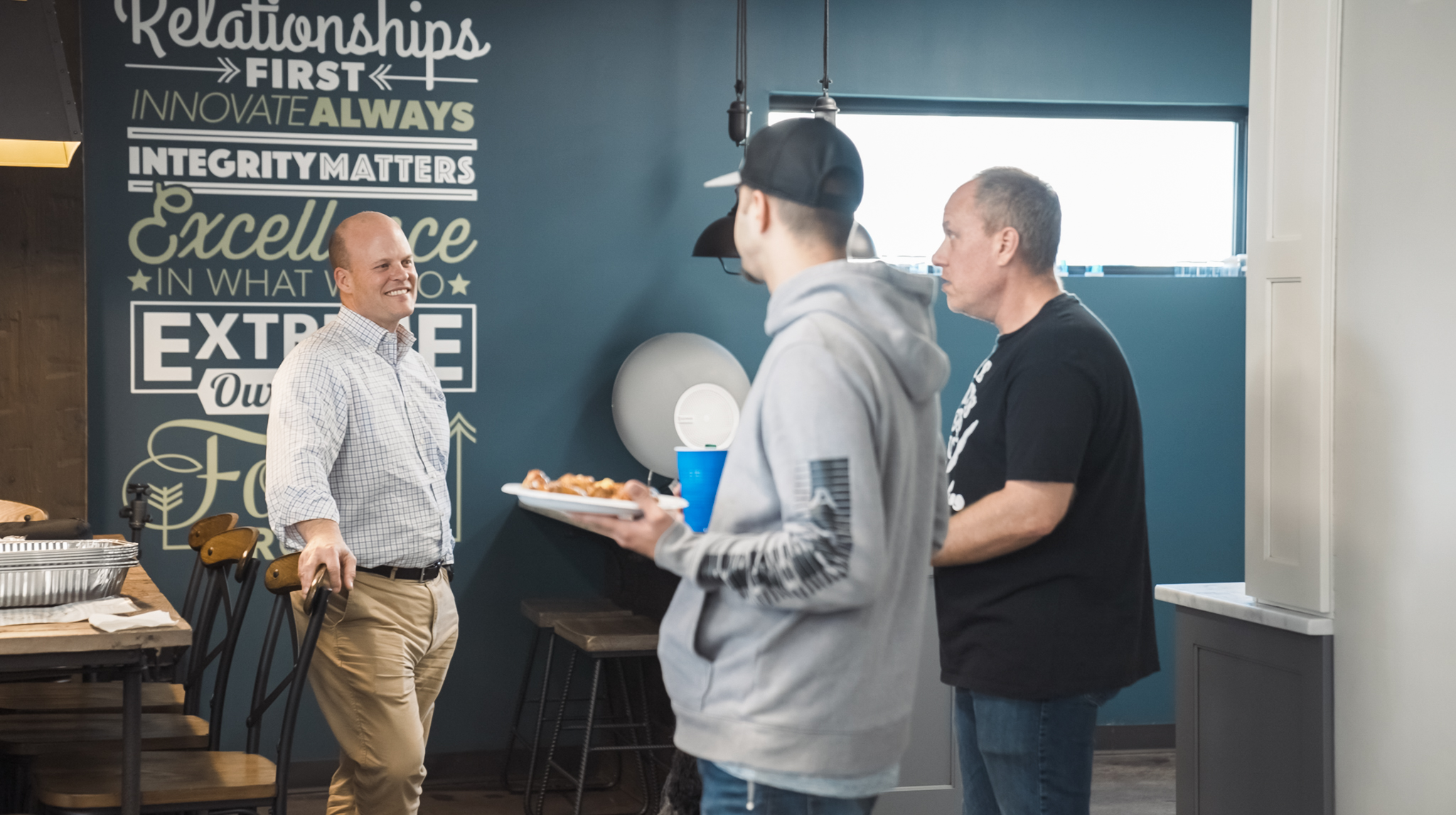 A group of men chatting in a room. DPM Surface Care Blog