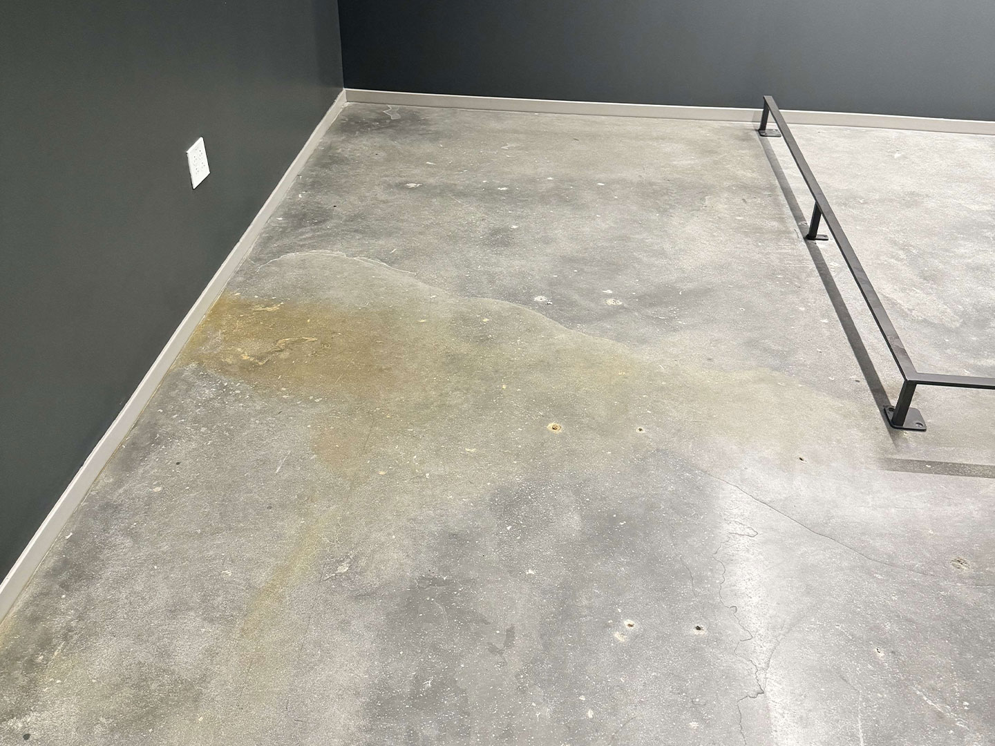 A concrete floor with a huge water stain, before interior concrete floor cleaning. DPM Surface Care