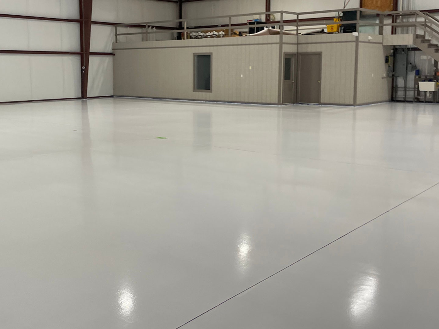 A spacious room with a clean and shiny floor and a loft. DPM Surface Care